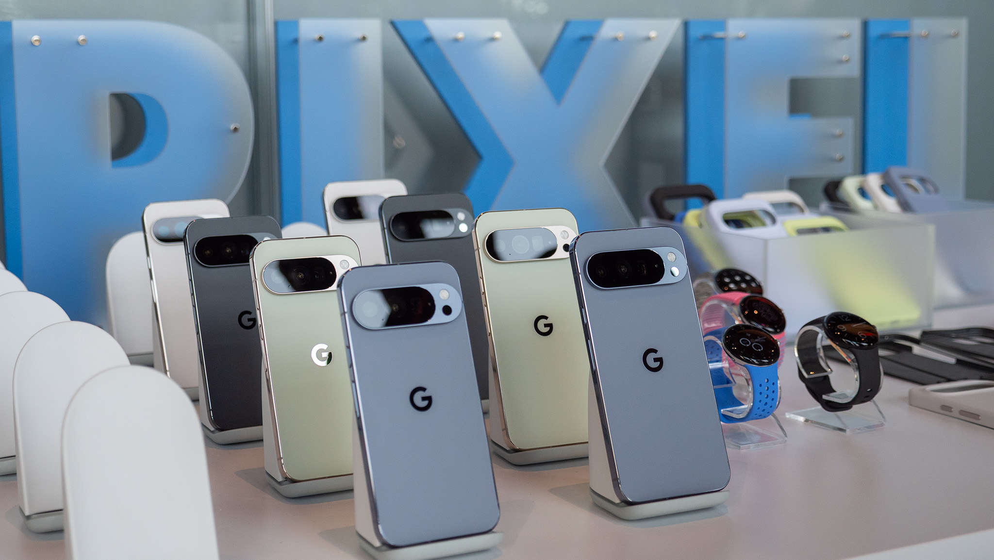 All colors of the Google Pixel 10 Pro and Pro XL line with a "PIXEL" sign behind them