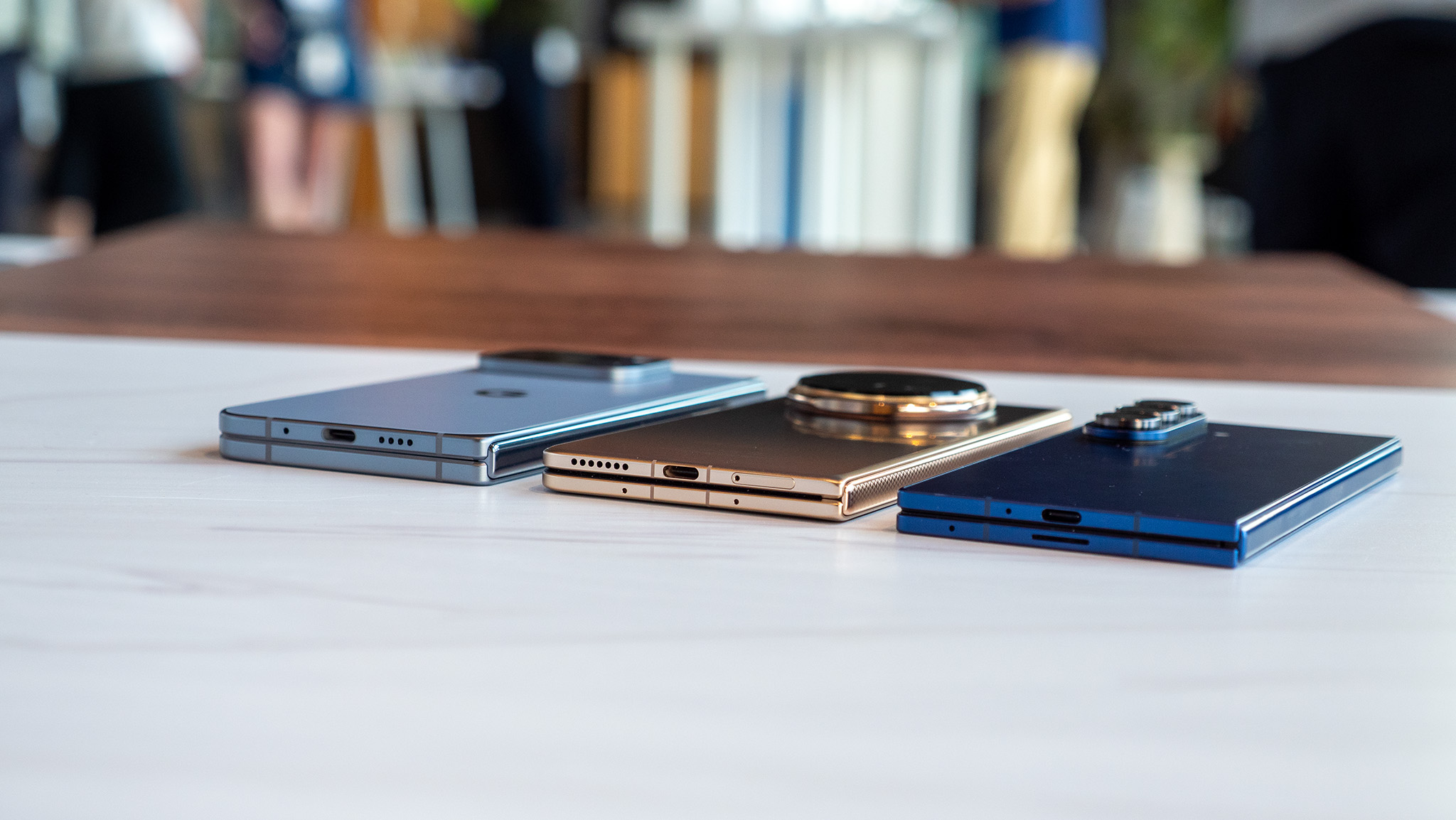 Comparing the size and thickness of the Google Pixel 10 Pro Fold (light blue), Honor Magic V5 (gold/copper), and Samsung Galaxy Z Fold 7 (dark blue)
